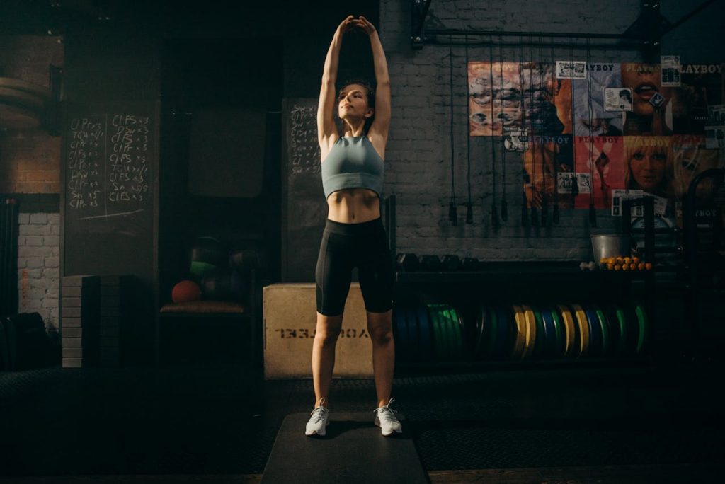 Mastering the First Impression: Your intriguing post title goes here Strong woman stretching her arms in an industrial-style gym environment with motivational wall art.